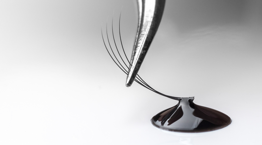 Tweezers dipping a volume lash fan in Goldlashbar lash glue